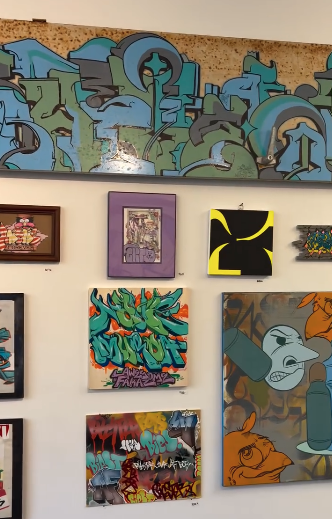 Gallery-style wall filled with colorful, diverse artworks in various sizes